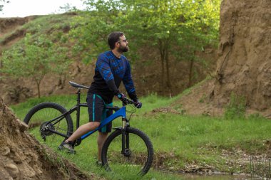 Şort ve mayo modern bir karbon hardtail bisiklet üzerinde bir hava süspansiyon çatal sürmek off-road turuncu-kırmızı tepelerde yaz aylarında gün batımı akşamı