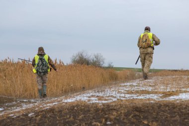 Male hunters with shotguns hunting outdoors
