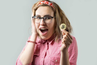 Young caucasian girl in glasses with crypto coin on white background