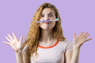 Beyaz bir arka plan üzerinde izole diş fırçası tutan kırmızı kıvırcık saçlı gülümseyen sevimli bir kadın portresi