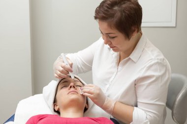 Yüz bakımı. Güzellik uzmanı güzellik salonunda fırça kullanarak yüzüne güzellik maskesi takıyor.