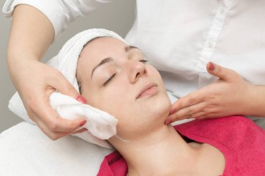 Yüz bakımı. Güzellik uzmanı güzellik salonunda fırça kullanarak yüzüne güzellik maskesi takıyor.