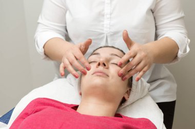 Yüz bakımı. Güzellik uzmanı güzellik salonunda fırça kullanarak yüzüne güzellik maskesi takıyor.