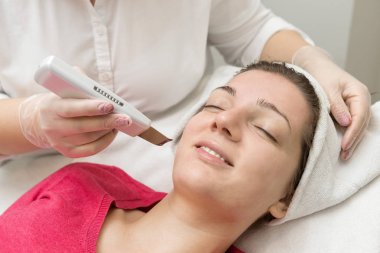 Yüz bakımı. Güzellik uzmanı güzellik salonunda fırça kullanarak yüzüne güzellik maskesi takıyor.