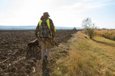 Sırt çantası ve sahada silahı olan bir avcı.