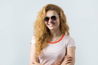 Uzun saçlı, beyaz tişörtlü ve gri gözlüklü güzel bir kadının portresi.