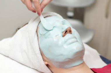 Kadın spa salonuna yüz maskesi takıyor.