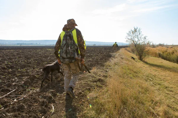 Sırt çantası ve sahada silahı olan bir avcı.