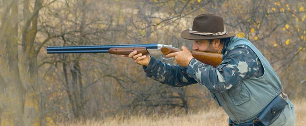 Hunter with a gun and a dog go on the first snow in the steppe, Hunting pheasant in a reflective vest