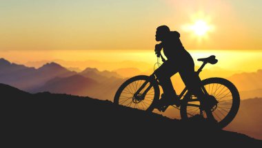 Şort ve mayo modern bir karbon hardtail bisiklet üzerinde bir hava süspansiyon çatal sürmek off-road turuncu-kırmızı tepelerde yaz aylarında gün batımı akşamı