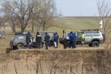 SUV arabalarının yanında bir grup insan.