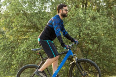 Parktaki bisikletli genç adam.