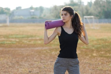 Spor kıyafetli, yılan derisi izli genç, zayıf bir atletik kız bir takım egzersizler yapıyor, karın kaslarını çalıştırıyor..