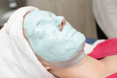Genç kadın Spa salonu ile yüz maskesi içinde