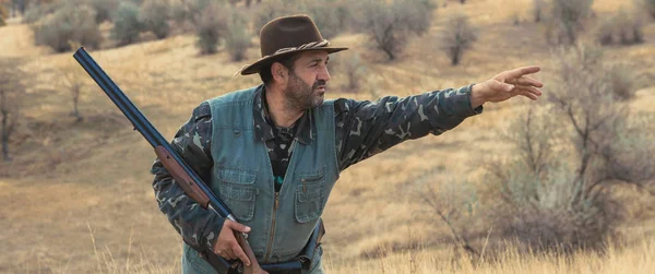 Hunter with a gun and a dog go on the first snow in the steppe, Hunting pheasant in a reflective vest