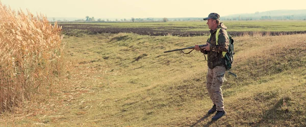 Hunter with a gun and a dog go on the first snow in the steppe, Hunting pheasant in a reflective vest