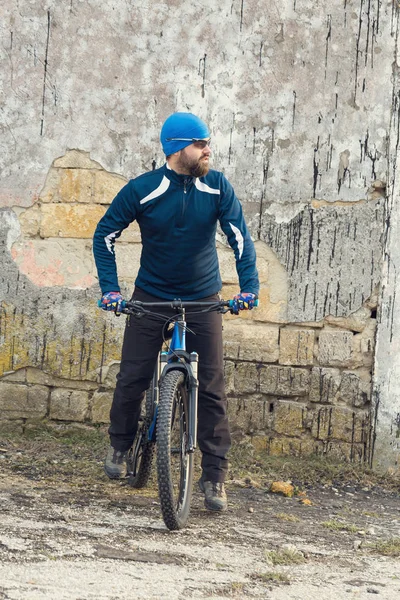 Cyclist in shorts and jersey on a modern carbon hardtail bike with an air suspension fork rides off-road on the orange-red hills at sunset evening in summer