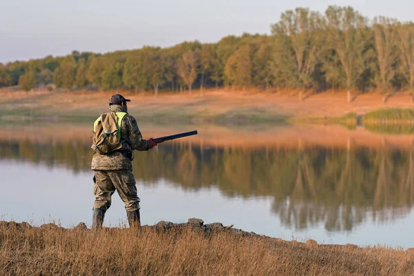 Hunter with a gun and a dog go on the first snow in the steppe, Hunting pheasant in a reflective vest