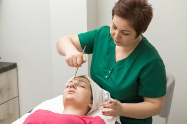 Genç bir kadın güzellik salonunda yüz masajı yaptırıyor.