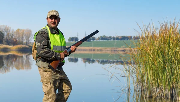 Hunter with a gun and a dog go on the first snow in the steppe, Hunting pheasant in a reflective vest