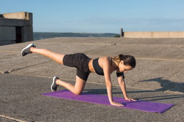 Güzel ince atletik kız egzersizleri açık havada bir dizi gerçekleştirir. Yoga yapmaktan özgürlük duygusu.