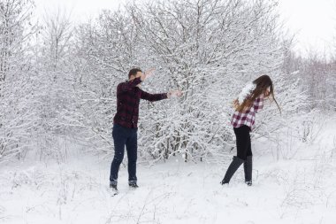 Adam ve kız kış ormanlarında dinleniyorlar. Karda karı-koca. Genç bir çift kış parkında yürüyor.