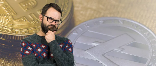 A pensive guy with a beard and glasses against a background of Bitcoin. Thinking about question, pensive expression, looks incredulous. Change in the growth and fall of cryptocurrency.