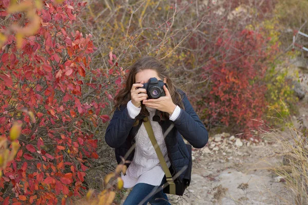 Sonbahar ormanında kameralı genç bir kadın.