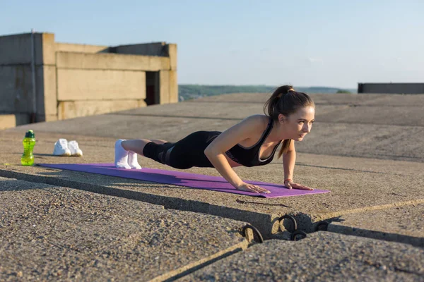 Spor giyimli, yılan derisi baskılı genç ve zayıf bir atletik kız bir takım egzersizler yapıyor. Fitness ve sağlıklı yaşam tarzı.