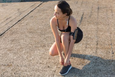 İnce atletik kız bitmemiş bir binanın çatısında germe egzersizleri gerçekleştirir, kentsel arka plan.