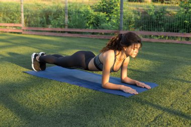 Spor giyimli, yılan derisi baskılı genç ve zayıf bir atletik kız bir takım egzersizler yapıyor. Fitness ve sağlıklı yaşam tarzı.