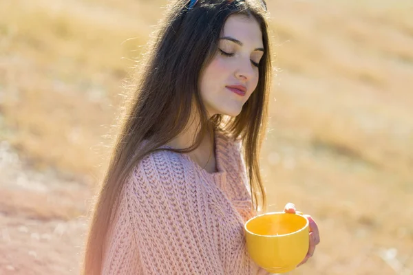 Parkta kahve içen genç bir kadın.