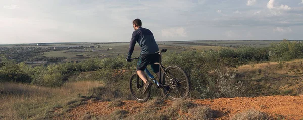 Şortlu ve formalı bisikletçilerle dağ zirvelerini hava askı çatalıyla modern bir karbon kuyruklu bisikletle fethetmek. Dağdan manzara çok güzel. Panoramik pankart görünümü.