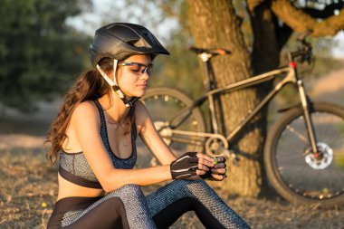 Offroad bir dağ bisikleti kız, gün batımında bir bisikletçi güzel portre, Fitness kız spor modern bir karbon fiber dağ bisikleti sürmek. Kız özgürlük ve rahatlama doğru bakar.