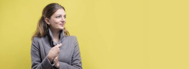 Paltolu genç bir kız sarı arka planda bir stüdyoda poz veriyor..