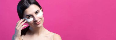 Çıplak omuzlu, göz altı yamalı oldukça çekici bir kızın portresi. Pembe arka planda duruyor.