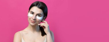 Çıplak omuzlu, göz altı yamalı oldukça çekici bir kızın portresi. Pembe arka planda duruyor.