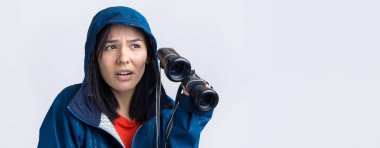 Mavi yağmurluklu bir turist kız elinde dürbünle uzaklığa bakıyor, casuslar..