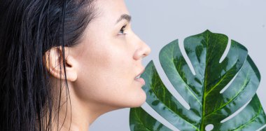 Doğal yeşil palmiye yaprağı portresi olan bir kadın. Moda, güzellik, makyaj, kozmetik.