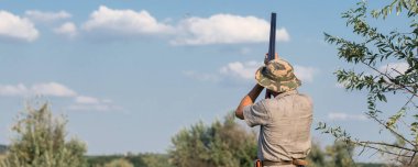 Sazlıklarda güneşe karşı silahlı bir avcının silueti. Köpekli ördekler için bir pusu.