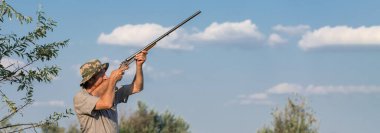 Sazlıklarda güneşe karşı silahlı bir avcının silueti. Köpekli ördekler için bir pusu.