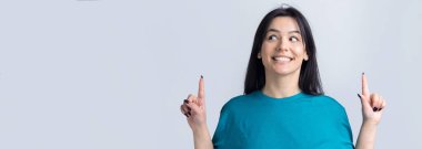 Mavi tişörtlü, parmaklarını gösteren mutlu beyaz kadın.