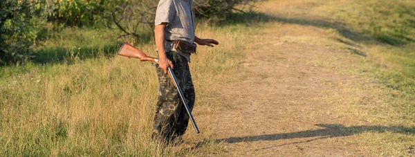 太陽に対する葦の銃を持つハンターのシルエット 犬とアヒルのための待ち伏せ — ストック写真