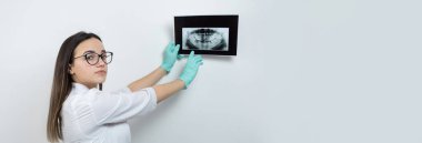 Beyaz önlüklü kız dişçi hastanın dişlerinin fotoğrafını tutuyor..