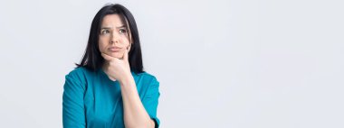 Mavi tişörtlü güzel bir kızın portresi, düşünceli bir ifadeyle yan yana bakmak, ilerisi için bir plan düşünüyor..