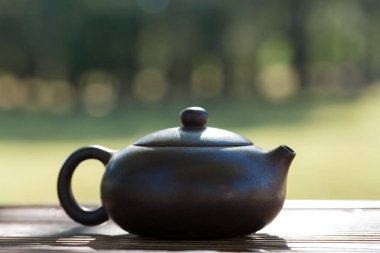 Çin çay seremonisi. Balçıktan yapılmış seramik çaydanlık ve ahşap bir arka planda kaseler.