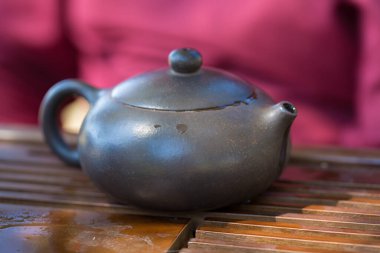 Çin çay seremonisi. Balçıktan yapılmış seramik çaydanlık ve ahşap bir arka planda kaseler.