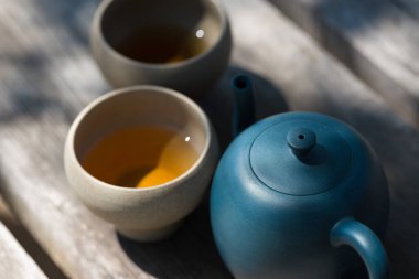 Çin çay seremonisi. Balçıktan yapılmış seramik çaydanlık ve ahşap bir arka planda kaseler.