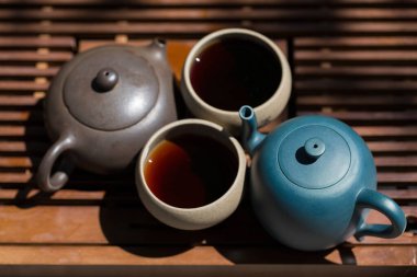 Çin çay seremonisi. Balçıktan yapılmış seramik çaydanlık ve ahşap bir arka planda kaseler.