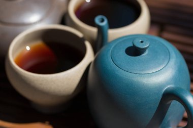 Çin çay seremonisi. Balçıktan yapılmış seramik çaydanlık ve ahşap bir arka planda kaseler.